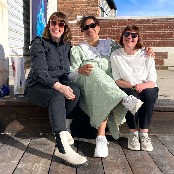 Lori Anderson, Alberta Whittle and Amanda Catto sit outside in the sunshine