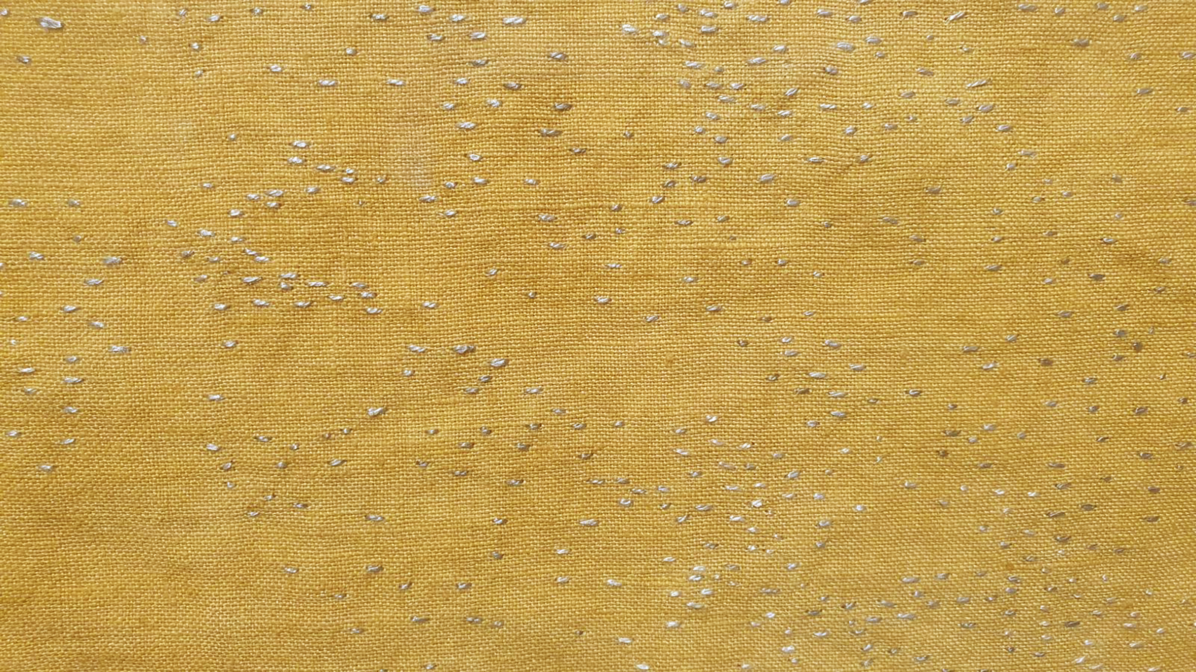 A close-up photograph of artwork in the exhibition that is made out of golden yellow material and thread.